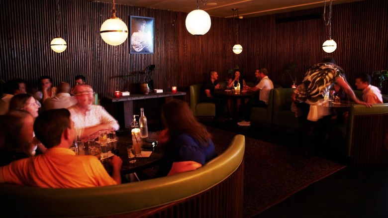 People sitting in green banquettes at a cocktail bar