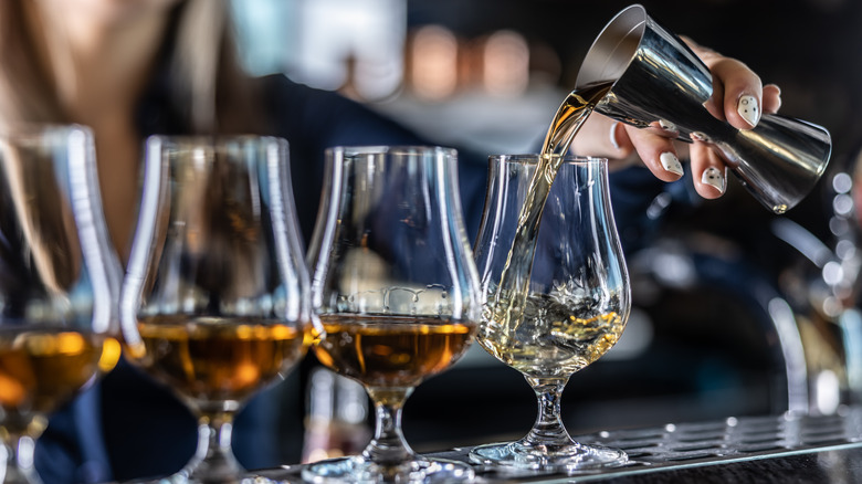 Bartender pouring whiskey into tasting glass