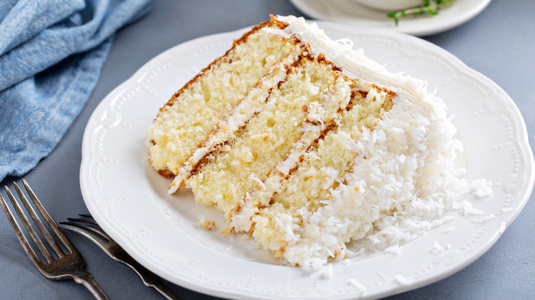 A slice of coconut cake on a white plate