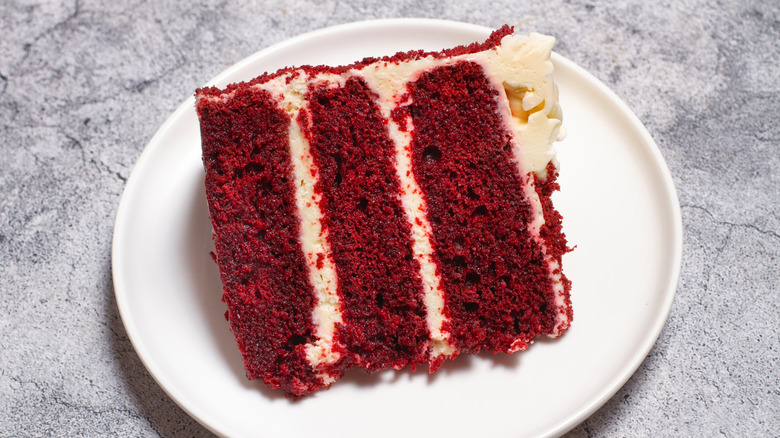 A classically striking slice of red velvet cake on a round white plate