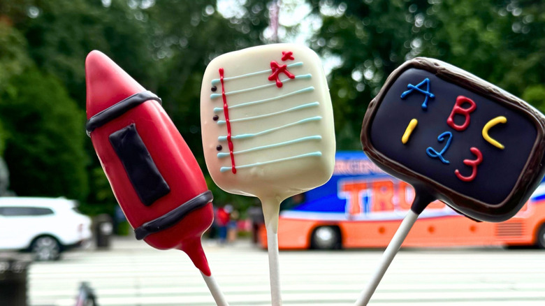 Someone holding up three school themed cakepops