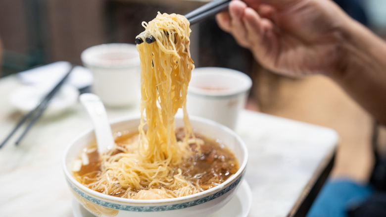 person using chopsticks to eat noodles