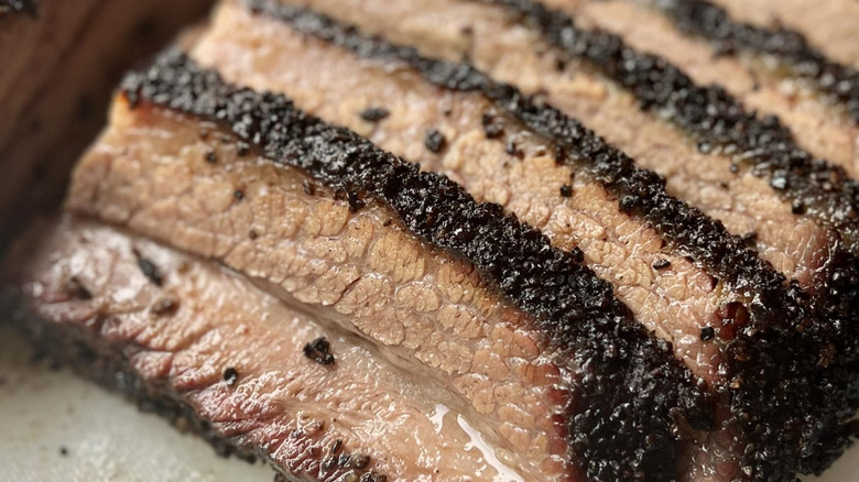 Juicy sliced brisket with a dark bark on a cutting board