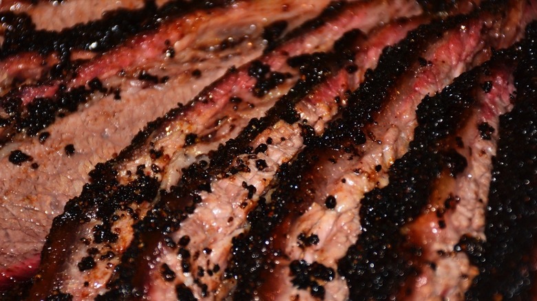 Closeup of sliced brisket, visibly moist with crumbly dark bark and bright red smoke rings