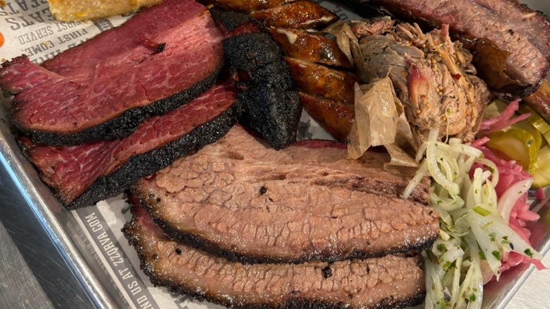 A tray of different meats and sides, including slices of brisket