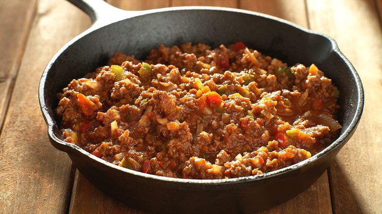 Cast iron skillet filled with sauce-covered ground beef and peppers