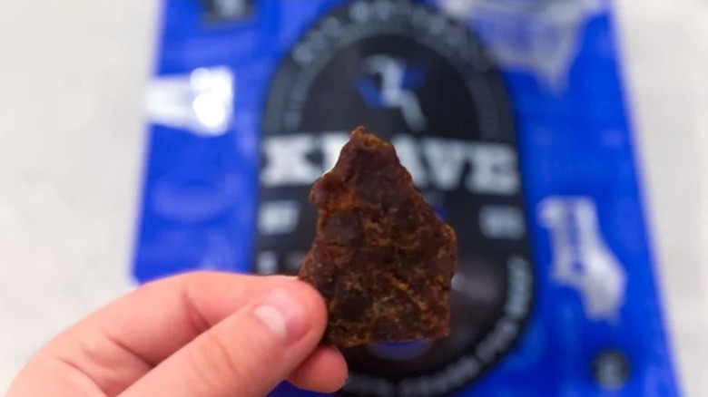 Hand holding up a piece of Krave beef jerky