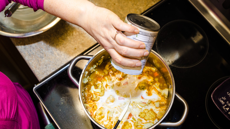 Pouring coconut milk into saucepan