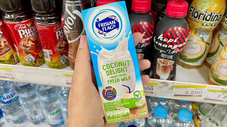Hand holding boxed coconut milk at a grocery store