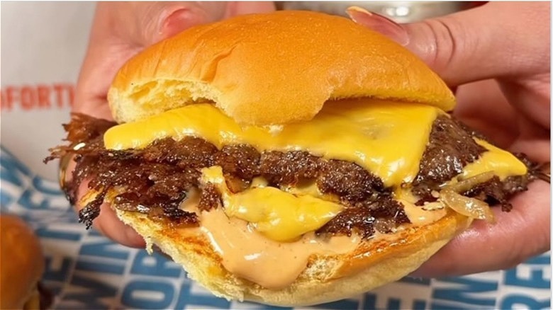 A double cheeseburger from For The Win burgers being held up in someone's hands