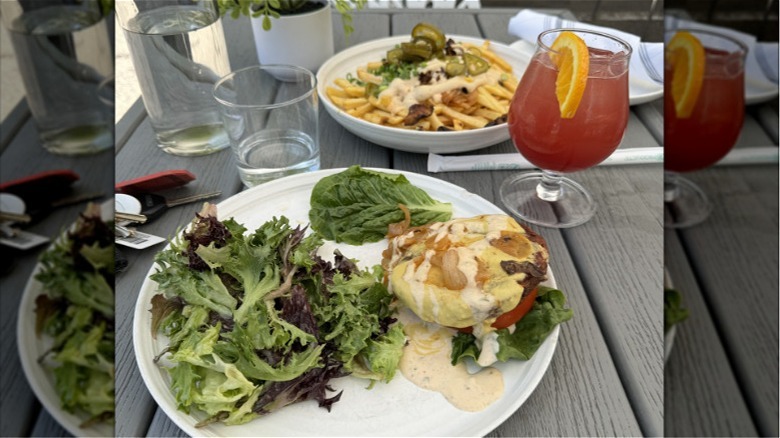 Plant City X burger with french fries and a cocktail in the background