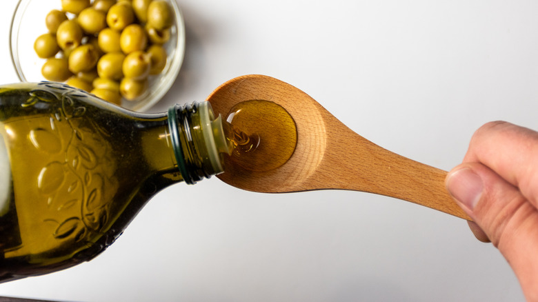 Olive oil pouring into a wooden spoon