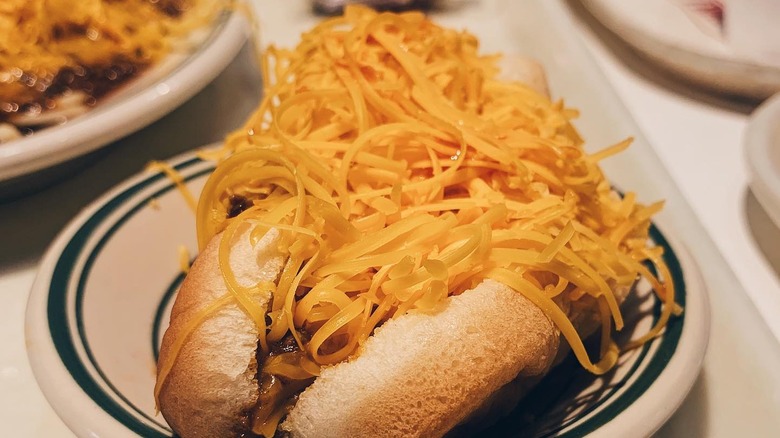 A chili dog covered in cheese sitting on a plate