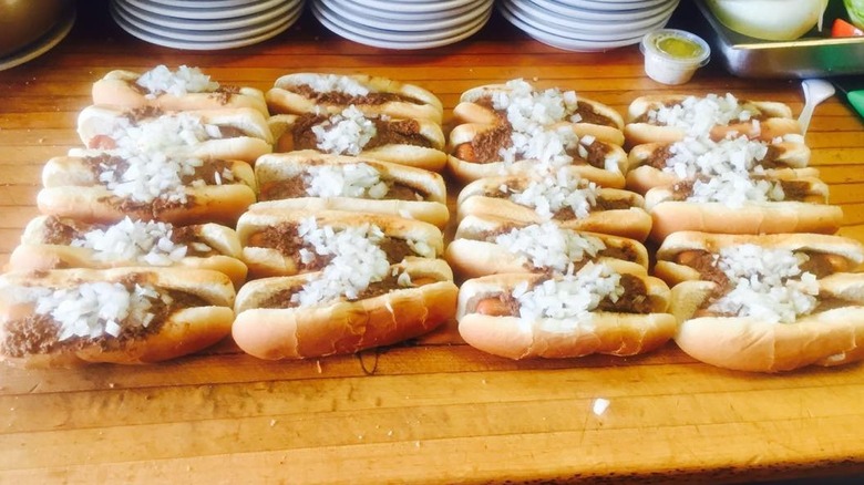A bunch of chili dogs laid out on the counter