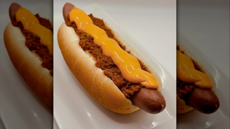 A chili dog with cheese on top