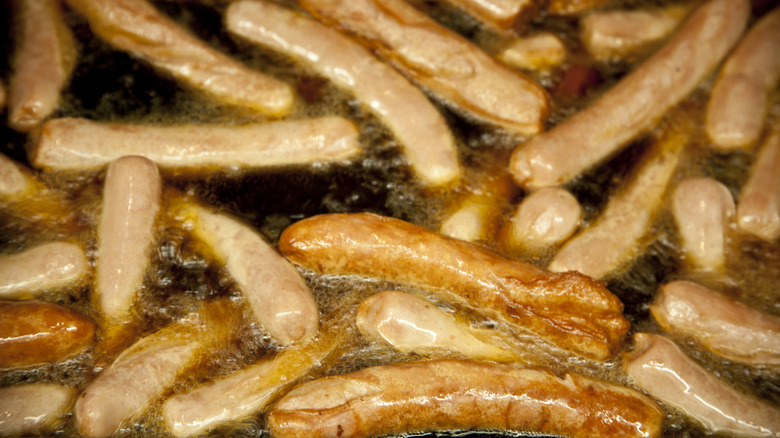 A bunch of hot dogs frying in oil