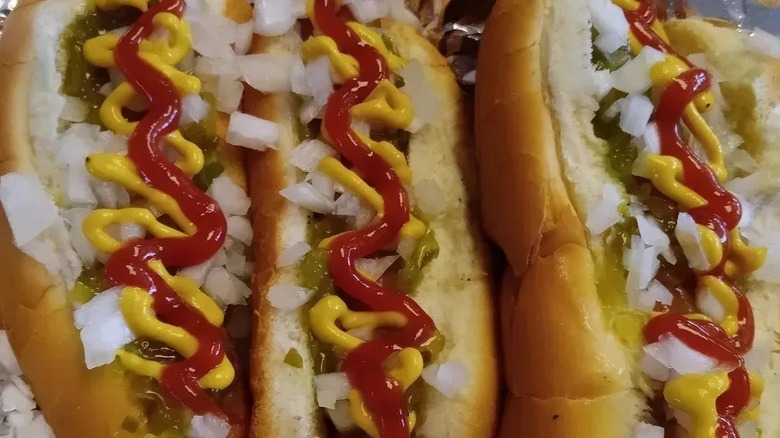 A line of hot dogs with ketchup, mustard, and other toppings