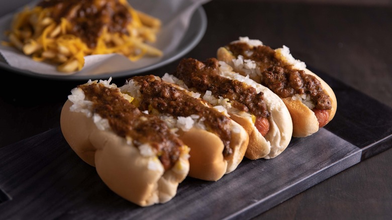 A line of chili dogs on a table