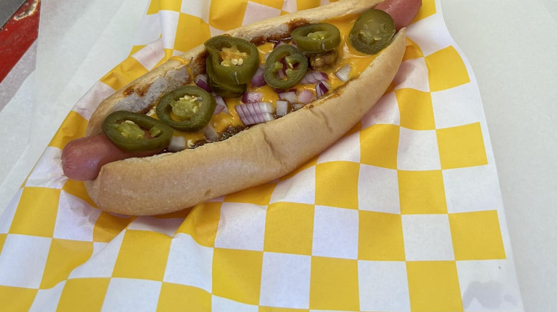 Close-up of a hot dog with jalapeños, cheese, and other toppings