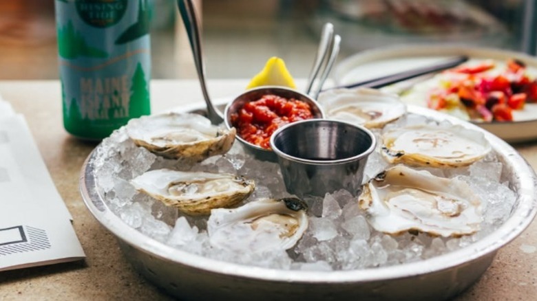 Oysters on ice with dipping sauces and a lemon wedge