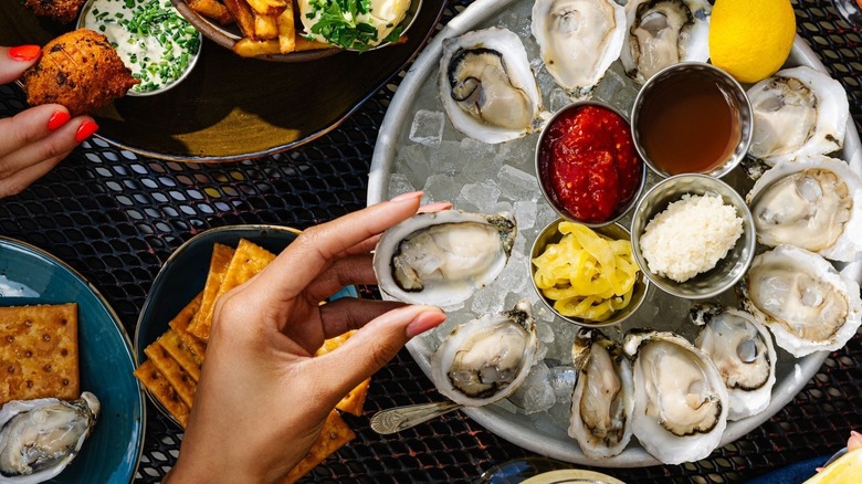 A person taking an oyster off a platter at St. Roch Fine Oysters + Bar