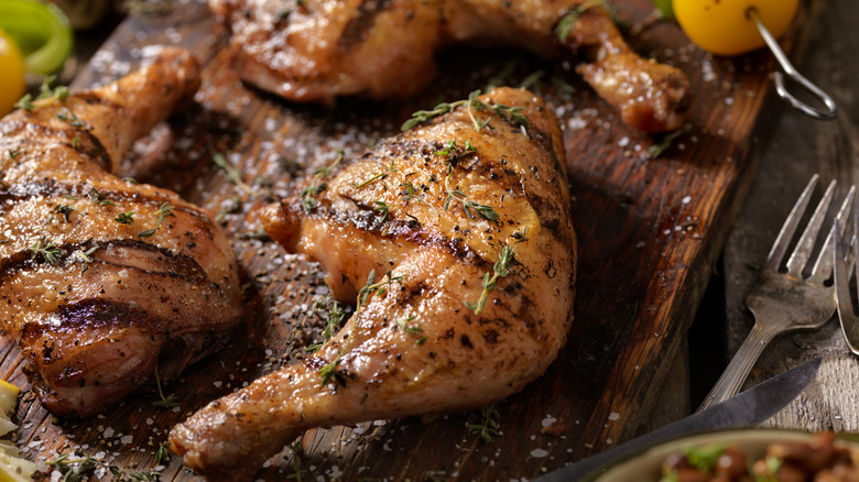 Beautifully grilled chicken legs on a wooden board.