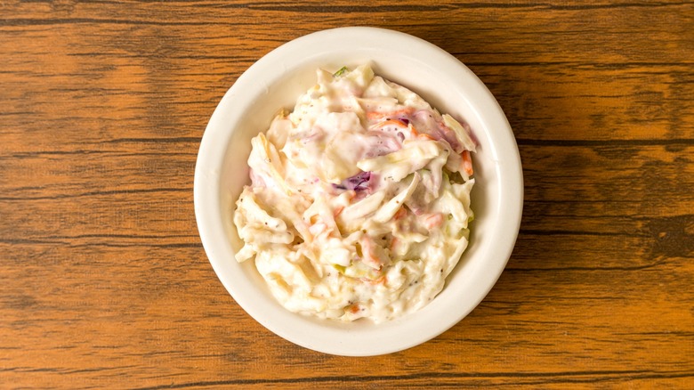 A dish of creamy coleslaw on old wooden table.
