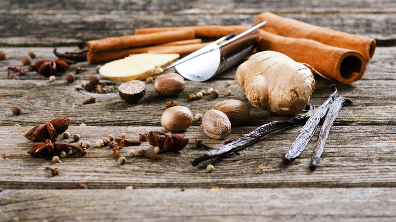 A combination of raw ingredients for spices, including cinnamon sticks, fresh ginger, and whole nutmeg