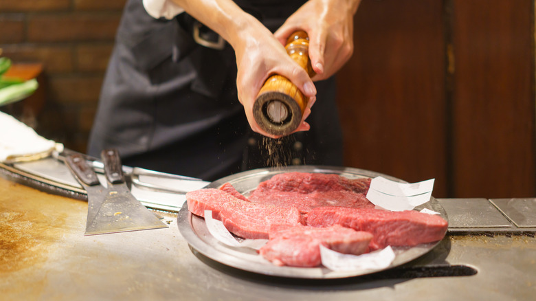 Salting raw steaks in the kitchen