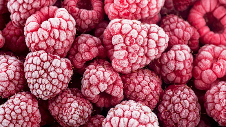 A pile of frozen raspberries with a layer of frost on them