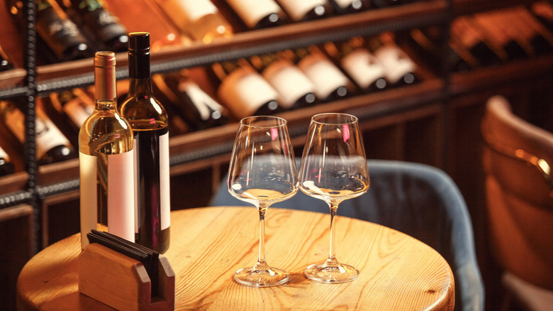 Wine bottles and glasses on a small table in a wine cellar