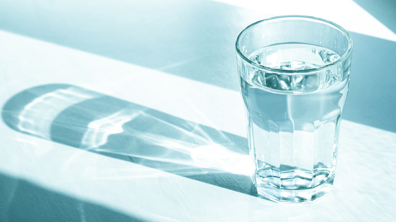 Glass of water in bluish light with a shadow