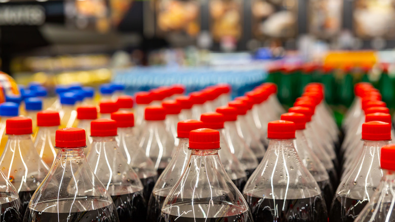 Rows of soda bottles with red and blue caps at a supermarket