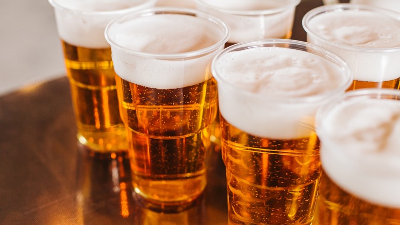 Several plastic cups filled with beer