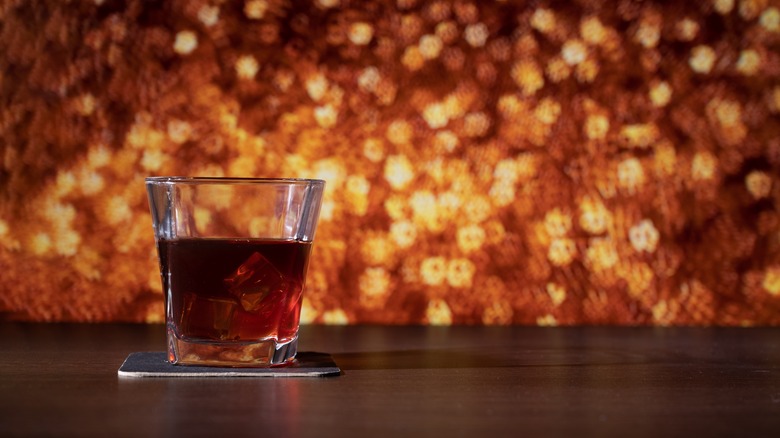 Glass of whiskey in front of golden, glittery holiday decoration