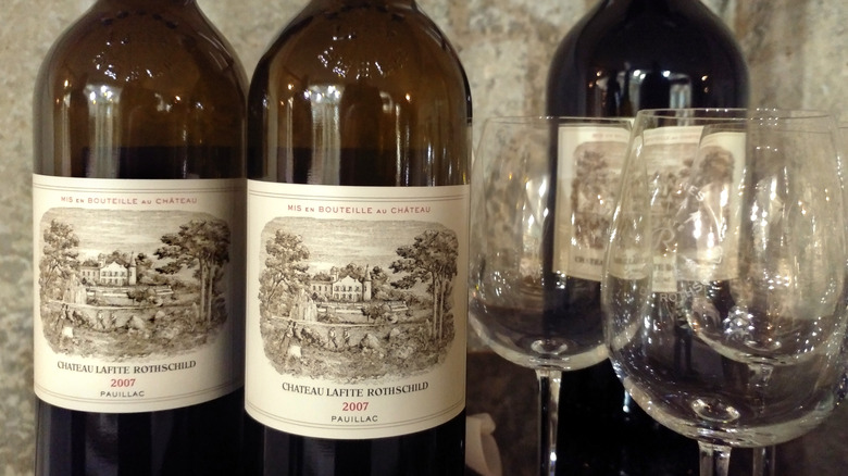 Bottles of Château Lafite Rothschild wine next to empty wine glasses