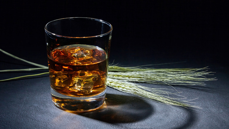 Glass of whiskey in front of ears of rye