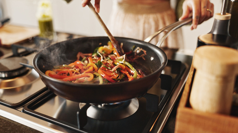 Person making a stove-top stir fry in pan
