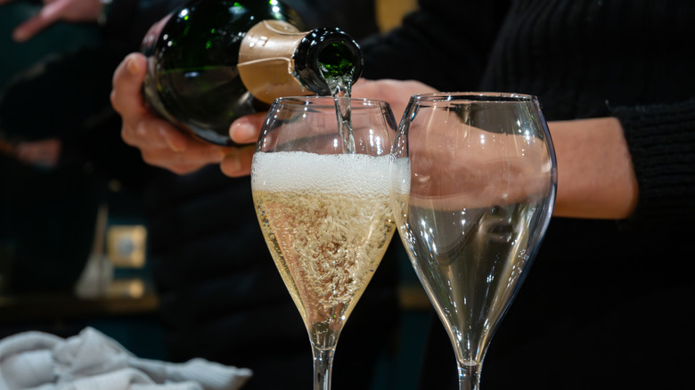 Somebody pouring sparkling wine into a glass