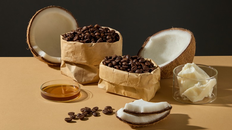 A halved coconut and open brown paper bags of coffee beans