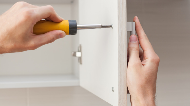 Hands installing cabinet hardware