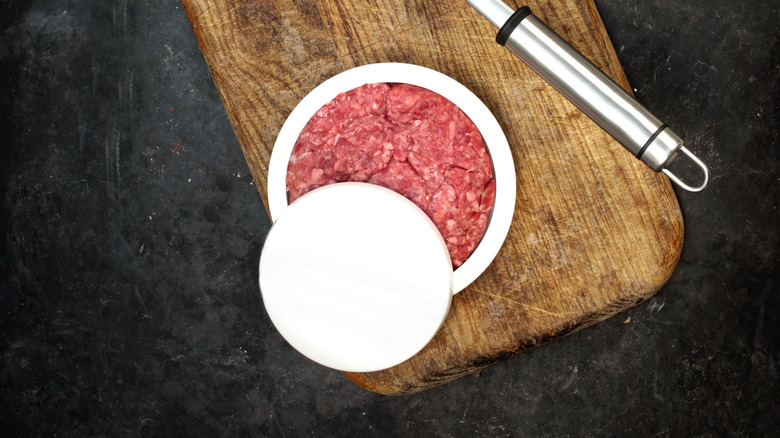 Plastic burger press with meat.