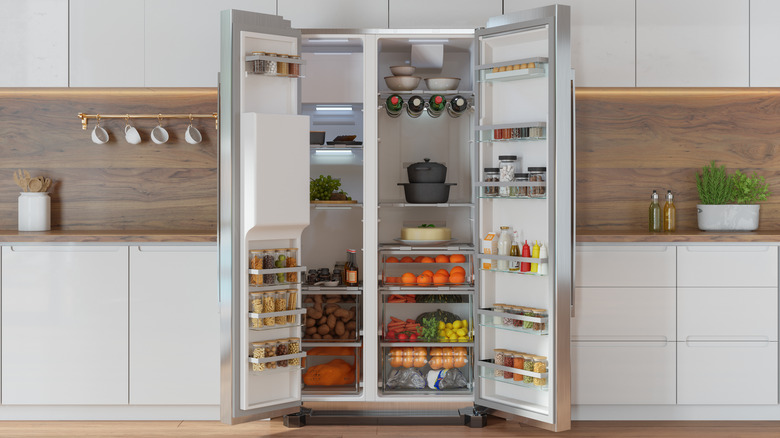 Refrigerator with open doors that's packed with food and fresh produce
