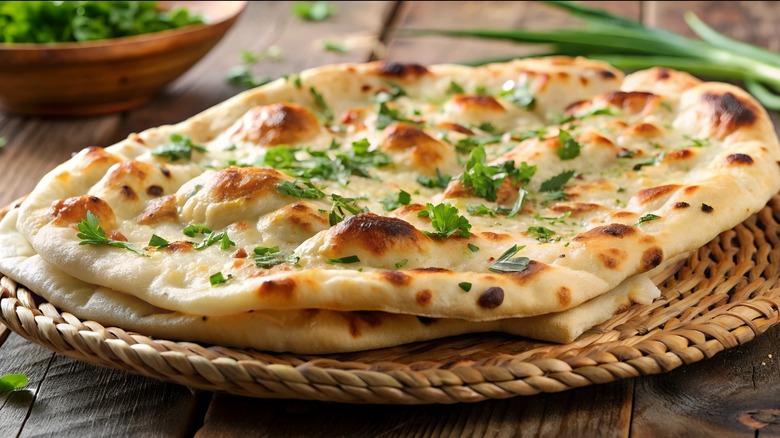 Fresh, herb-topped naan on a wicker platter