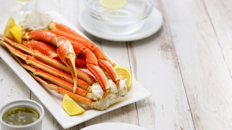 snow crab legs served in a plate with butter sauce and lemon