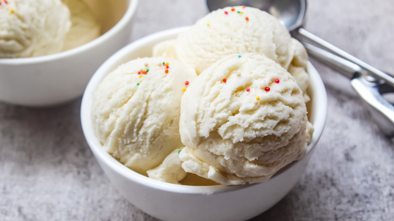 Bowl of vanilla ice cream with ice cream scoop