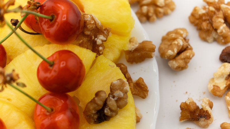 Shelled walnuts, cherries, and pineapple rings on a plate