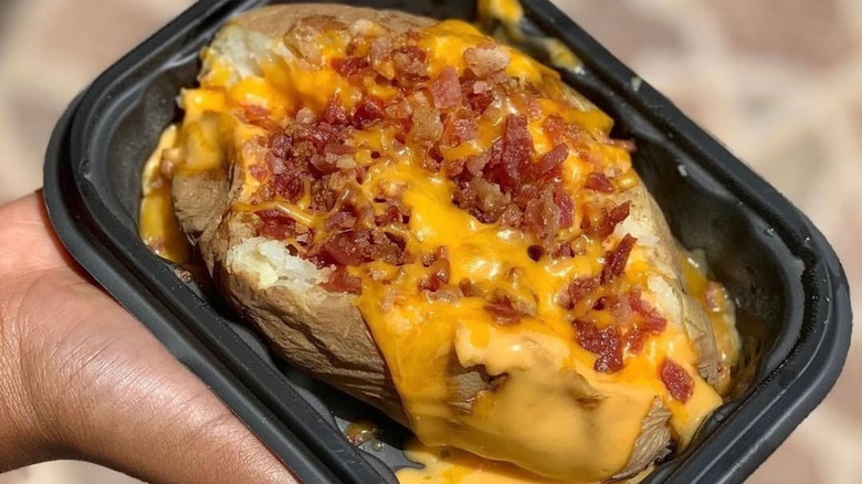 Person holding Wendy's chili and cheese baked potato