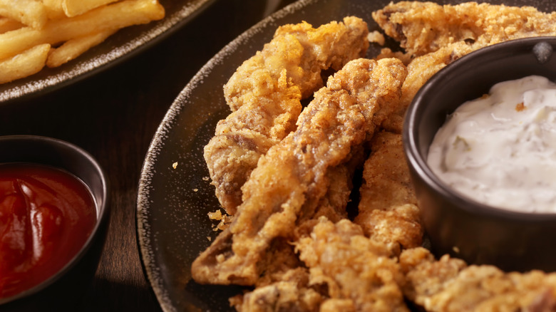close up of steak fingers on plate surrounded by sauces