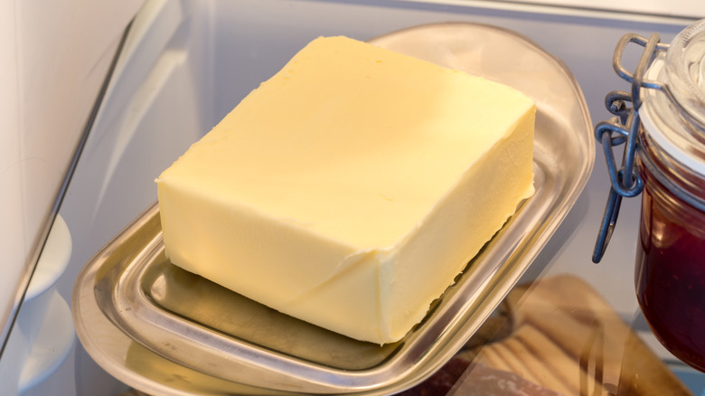 A cube of butter on a tray in a refrigerator.